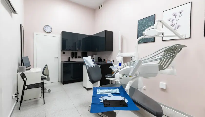 Nowoczesny gabinet stomatologiczny z fotelem dentystycznym i wyposażeniem.