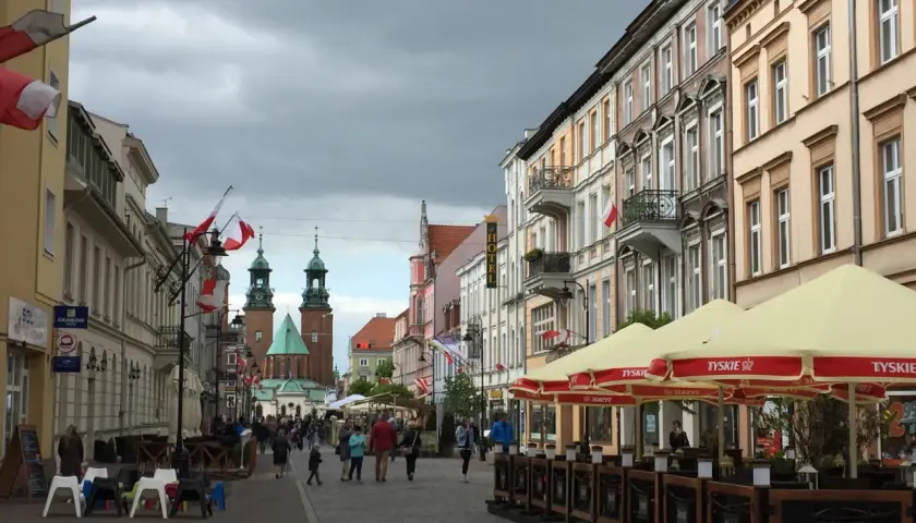 Spacer po Gnieźnie, gdzie widać zabytkowe kamienice, katedrę i ludzi odpoczywających w ogródku piwnym.