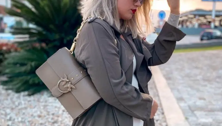 Elegancka torebka Pinko idealnie dopełnia stylowe torebka pinko stylizacje. Kobieta w płaszczu i okularach przeciwsłonecznych prezentuje modny dodatek.