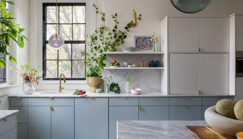 A modern kitchen with popular kitchen cabinet colors: soft blue lower cabinets and light gray upper cabinets, accented with brass hardware.