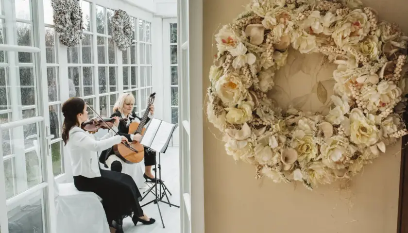 Dwie artystki tworzą oprawę muzyczną ślubu w kościele: jedna gra na skrzypcach, druga na gitarze.