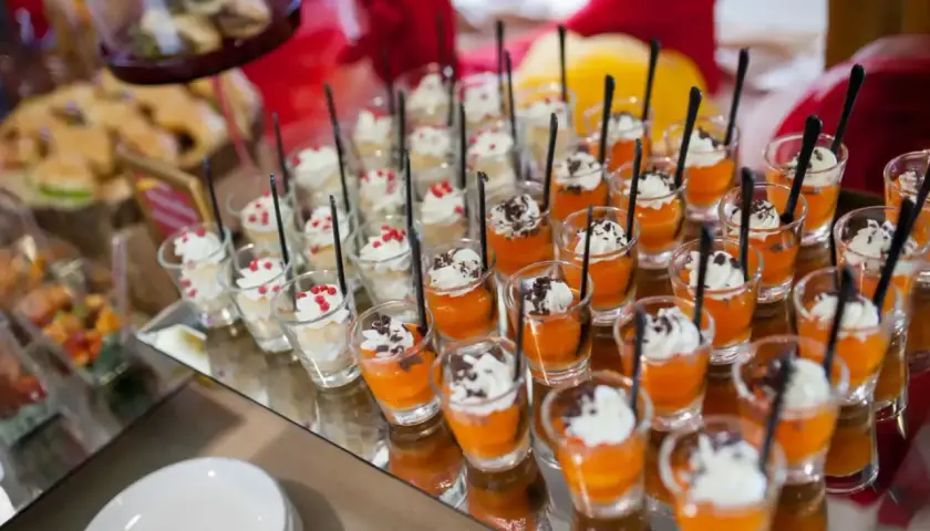 Petits desserts individuels en verrines, certains à la crème et fruits rouges, d'autres à la mousse orange et copeaux de chocolat. Un nom de menu original serait parfait pour ces délices.