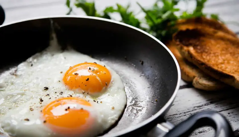 Deux œufs au plat parfaits dans une poêle, prêts à être dégustés. Une idée simple pour comment faire des oeufs au plat.