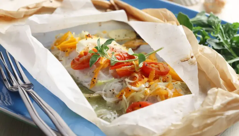 Un plat de cabillaud en papillote, garni de tomates cerises et d'herbes. Un délice pour savoir quel vin avec du cabillaud.