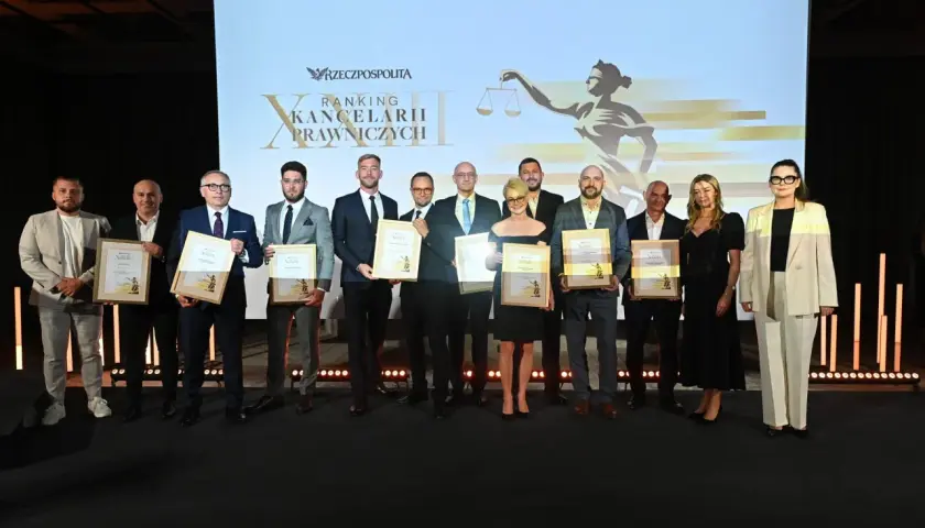 Grupa prawników odbiera nagrody na scenie przed ekranem z logo "Rzeczpospolitej" i grafiką Temidy.