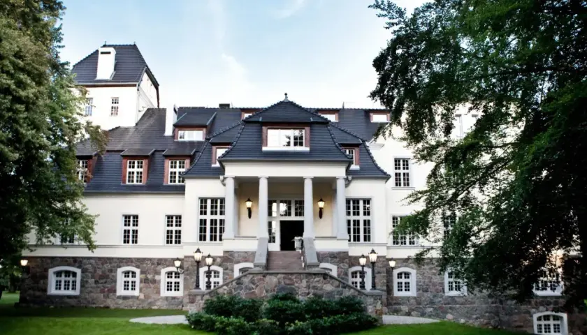 Elegancki pałac w Ciekocinku otoczony zielenią, z kamienną podstawą i kolumnowym wejściem.