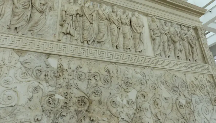 Bas-reliefs de l'Ara Pacis à Rome, représentant des figures toges et des motifs floraux complexes.