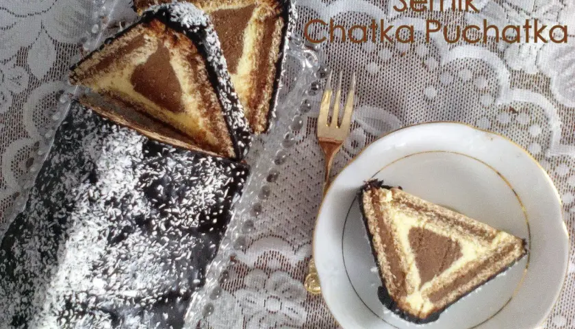 Sernik Chatka Puchatka, ciasto z sera z wiaderka, z polewą czekoladową i wiórkami kokosowymi. Na talerzyku kawałek ciasta.