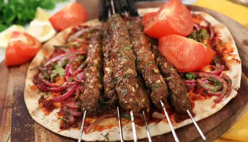Adana kebab recept: saftiga köttfärsspett på tunnbröd med rödlök, tomat och persilja. Enkel och god middag.