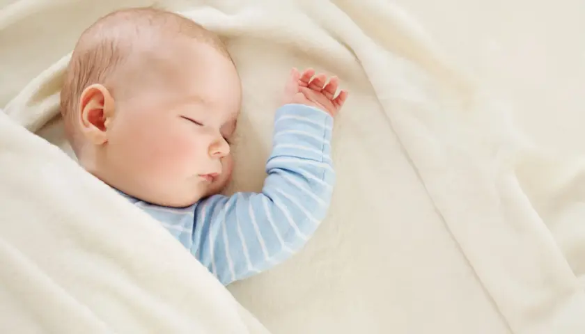 Śpiące dziecko, 22 tydzień życia, otulone w miękki kocyk.
