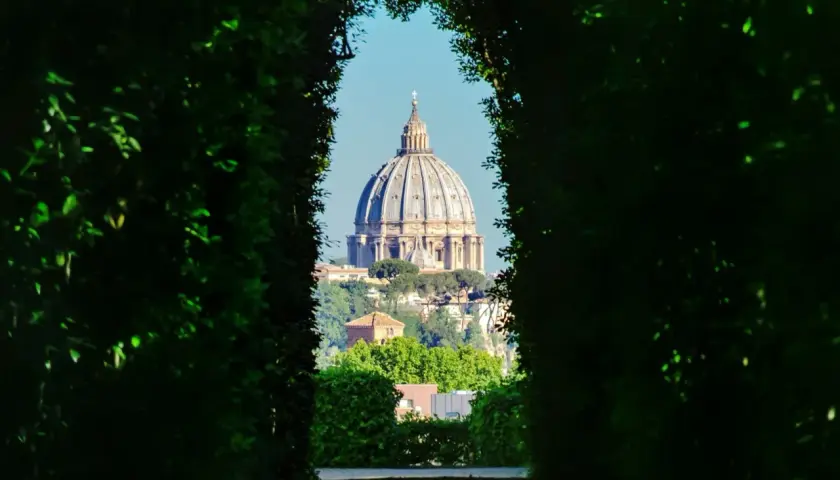 Blick durch grüne Hecken auf die Kuppel des Petersdoms. Ein versteckter Aussichtspunkt, einer der vielen Rom Geheimtipps.