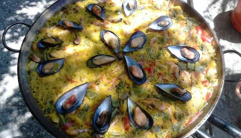 Una deliciosa fideuà mixta, con fideos dorados, mejillones jugosos y gambas, lista para compartir.