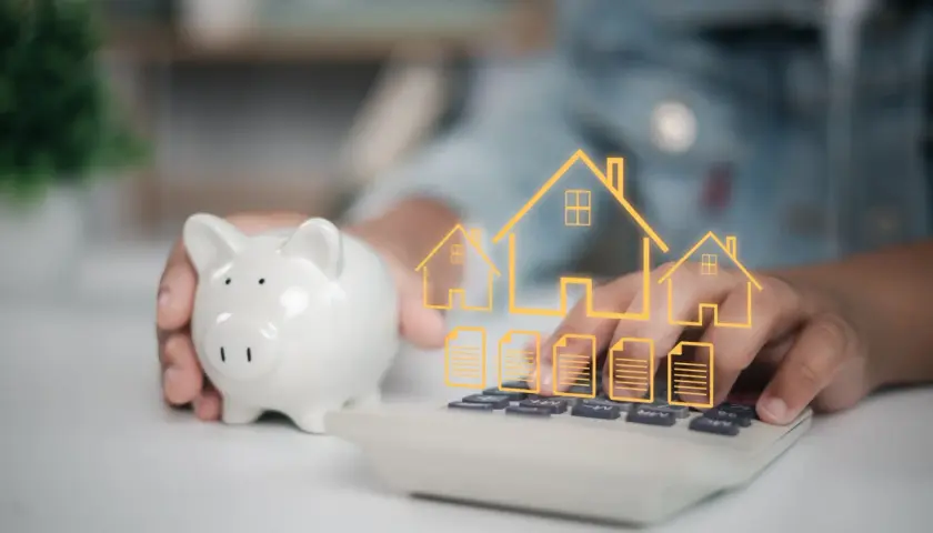 Une tirelire et une calculatrice avec des icônes de maisons et de documents. Une autre solution que le prêt relais pour financer votre projet immobilier.