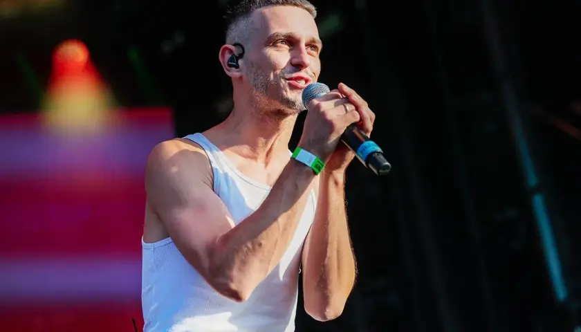 Vito Bambino na scenie, w białej podkoszulce, z mikrofonem w dłoni. Jego wzrost robi wrażenie.