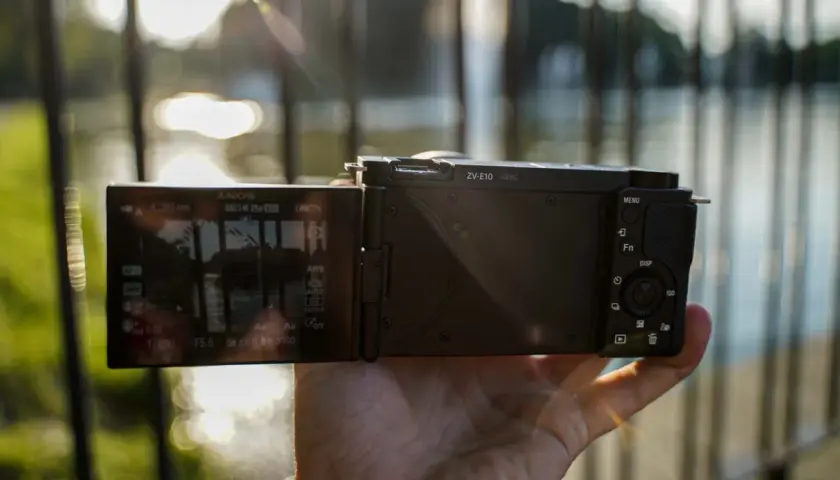 Dłoń trzyma aparat Sony Alpha ZV-E10 z uchylonym ekranem, na którym widać ustawienia nagrywania 4K.