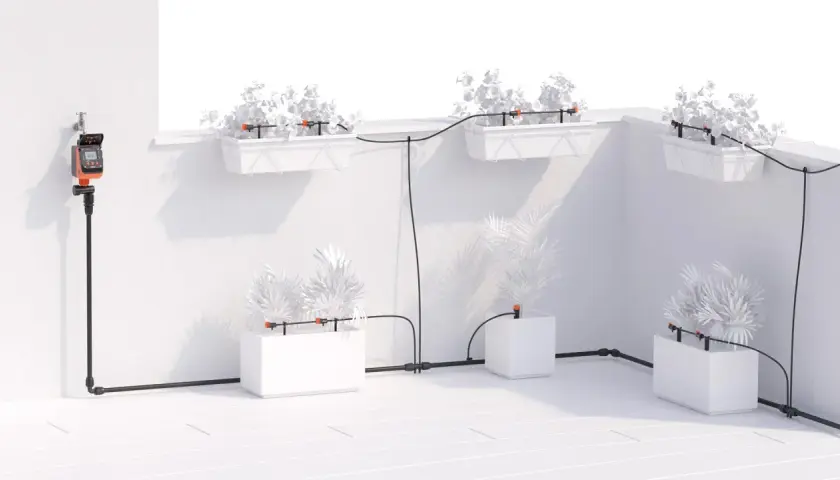 Sistema di irrigatore automatico per vasi fai da te con timer digitale collegato al rubinetto, che distribuisce acqua a piante in fioriere e vasi.