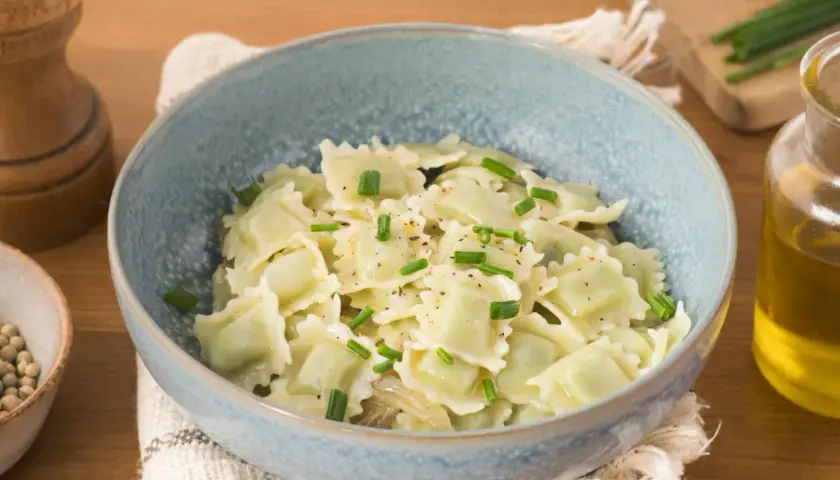 Un plat de ravioli du Dauphiné, généreusement garnis et saupoudrés de ciboulette fraîche et de poivre noir.