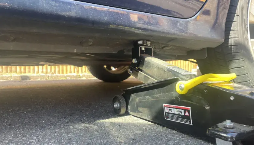 Lewarek podłożony pod wzmocnienie progu samochodu. Widać podnośnik i miejsce, gdzie podłożyć lewarek, by bezpiecznie podnieść auto.