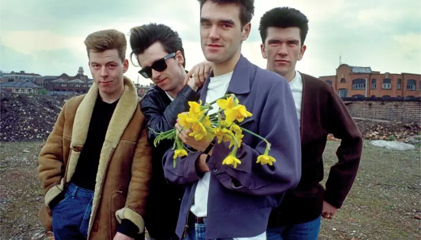 Członkowie The Smiths pozują z bukietem żółtych żonkili na tle postindustrialnego krajobrazu.