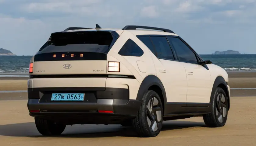 Kremowy Hyundai Nexo na plaży, z widokiem na morze i wyspę w oddali.