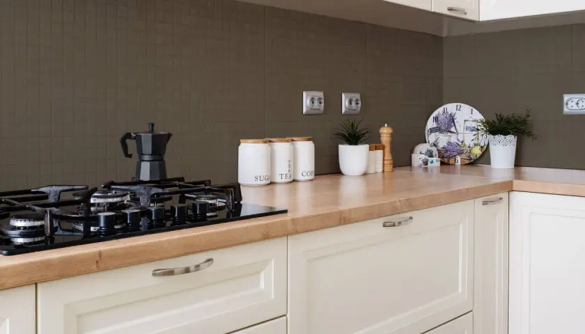 Fornelli neri su piano in legno, con barattoli per zucchero, tè e caffè. Sfondo con piastrelle effetto vernice per piastrelle cucina.