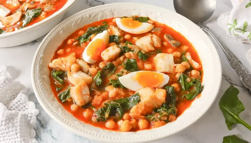 Un reconfortante potaje de vigilia con garbanzos, espinacas y trozos de pescado blanco, coronado con huevos duros.