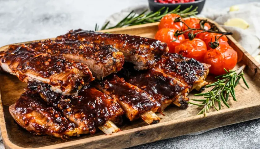 Soczyste żeberka w sosie barbecue, podane z pieczonymi pomidorkami i rozmarynem. Idealne danie, gdy zastanawiasz się, co zrobić z ugotowanych żeberek.