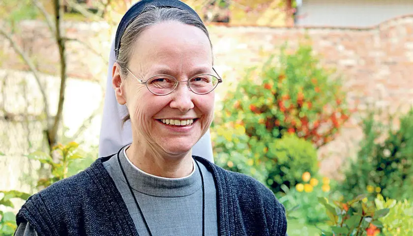 Lächelnde evangelische Nonne mit Brille im Garten.