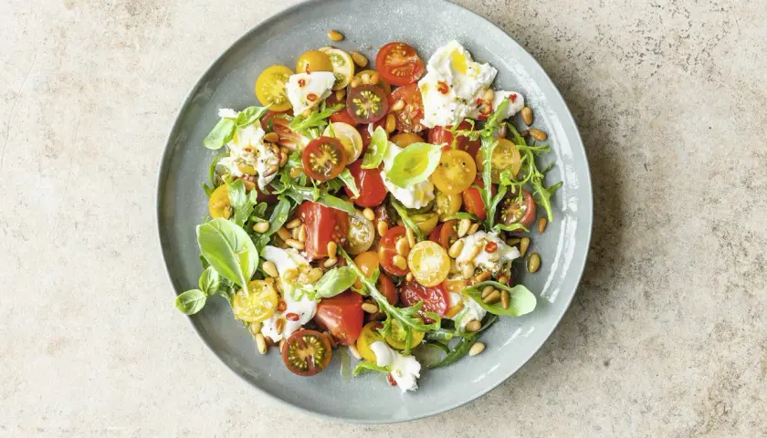 Bunter Tomatensalat mit Burrata, Rucola und Pinienkernen. Ein leichter Genuss für warme Tage.
