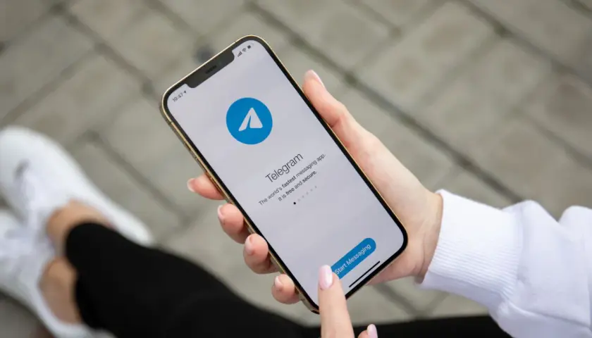 Dłoń trzyma smartfon z otwartą aplikacją Telegram, która reklamuje się jako szybka i bezpieczna. Czy telegram jest bezpieczny?