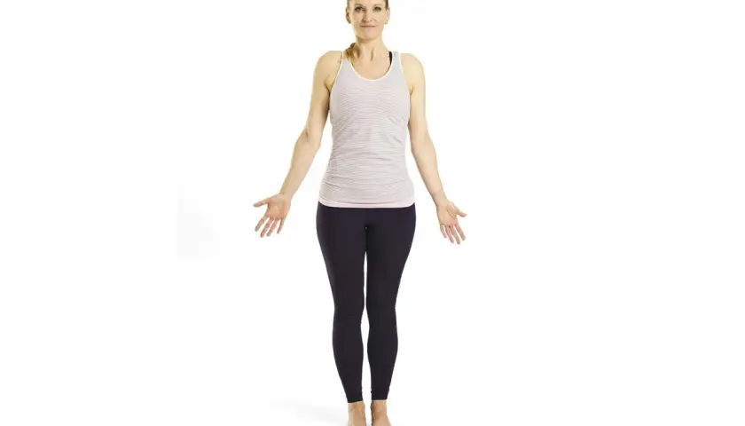 Krigaren yoga: kvinna i randig topp och mörka leggings står med armarna utåt, redo att möta dagen med styrka och lugn.