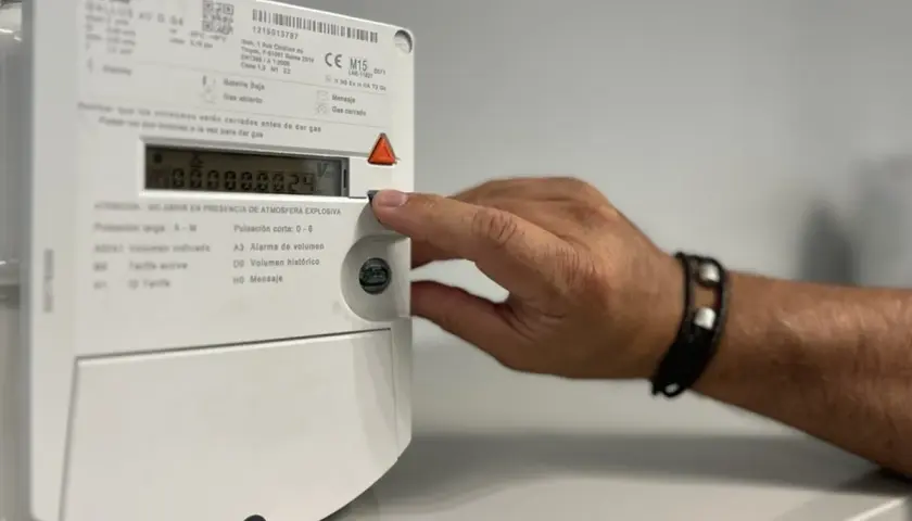Mano interactuando con un contador digital de gas.