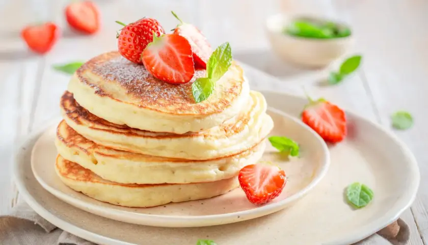Pile de pancakes moelleux, décorés de fraises fraîches et de menthe, comme ceux de Cyril Lignac. Un délice !
