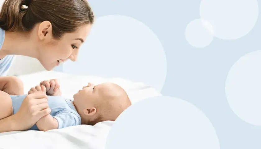 Mama patrzy z miłością na swoje dziecko, które właśnie zaczyna gaworzyć, wydając pierwsze dźwięki radości.
