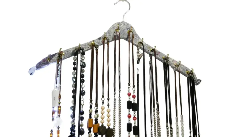 Percha para collares con multitud de cadenas y colgantes de diversos materiales y colores, organizados de forma ordenada.