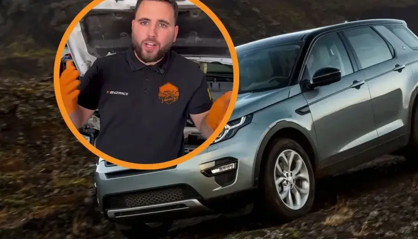 Opiniones sobre el motor Land Rover 3.0 TDV6. Mecánico con guantes naranjas habla junto a un Land Rover Discovery en terreno accidentado.