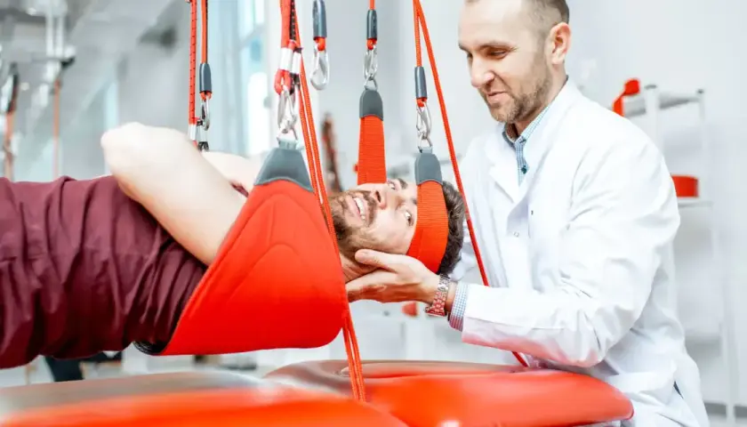 Fizjoterapeuta pomaga pacjentowi z bólem pleców podczas terapii wiszącej.