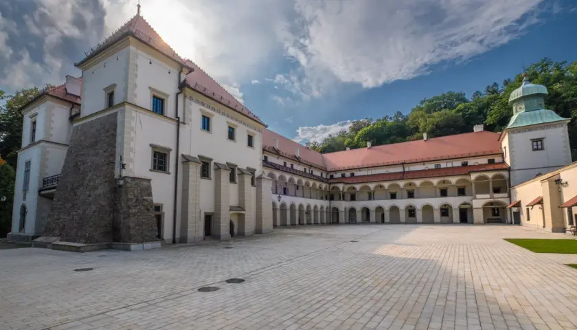 Dziedziniec zamku Sucha Beskidzka z arkadowymi krużgankami i wieżą.
