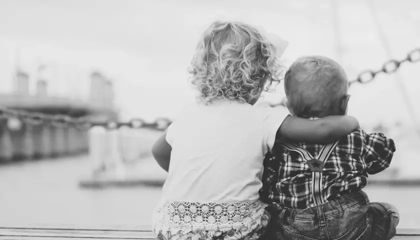 Due bambini, cugini, si abbracciano guardando il mare. Un tenero legame che ricorda un amore puro, lontano da ogni malizia.