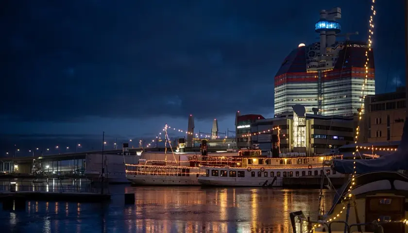 Nocny widok na port z oświetlonymi statkami i nowoczesnym budynkiem.