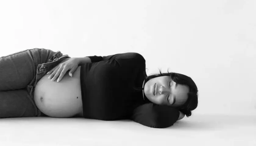 Donna incinta dorme serena, con la mano sul pancione. La vena cava è compressa, ma la serenità della gravidanza prevale.