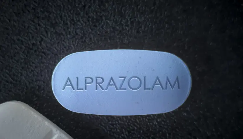 Niebieska tabletka z napisem "ALPRAZOLAM", który jest substancją czynną leku Xanax.