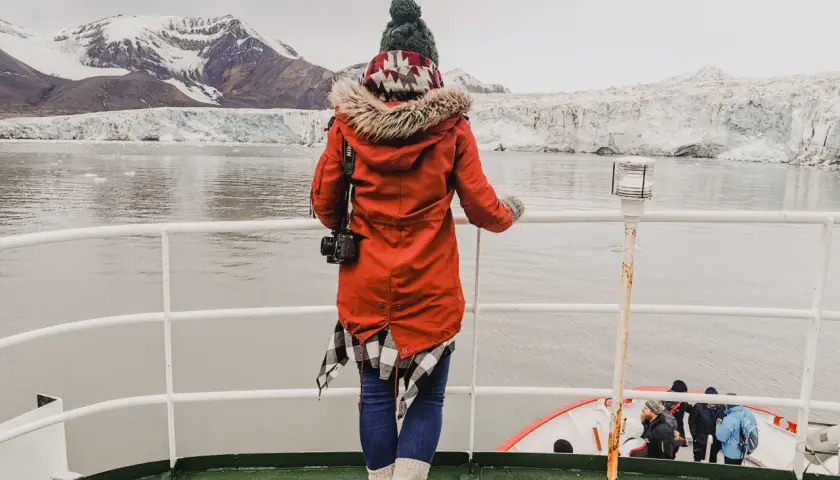 Podróżniczka podziwia lodowce na archipelagu Svalbard. W oddali widać góry i morze.