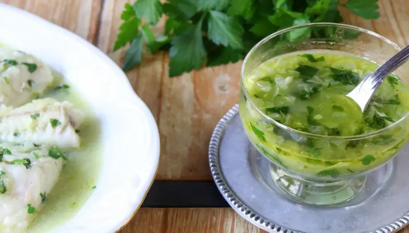 Pescado blanco bañado en una deliciosa salsa verde, con un cuenco de la misma salsa al lado.