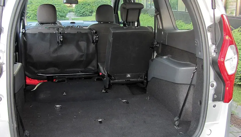 Pusta przestrzeń bagażnika Dacia Lodgy, gotowa na podróż. Widoczne złożone tylne siedzenia i siatka zabezpieczająca.