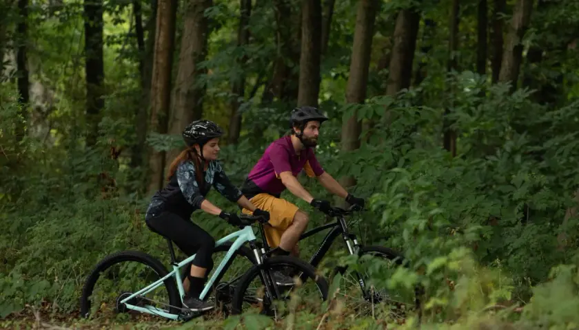 Para jadąca na rowerach górskich przez las. Czy to gravel, czy MTB? Wybór należy do nich.