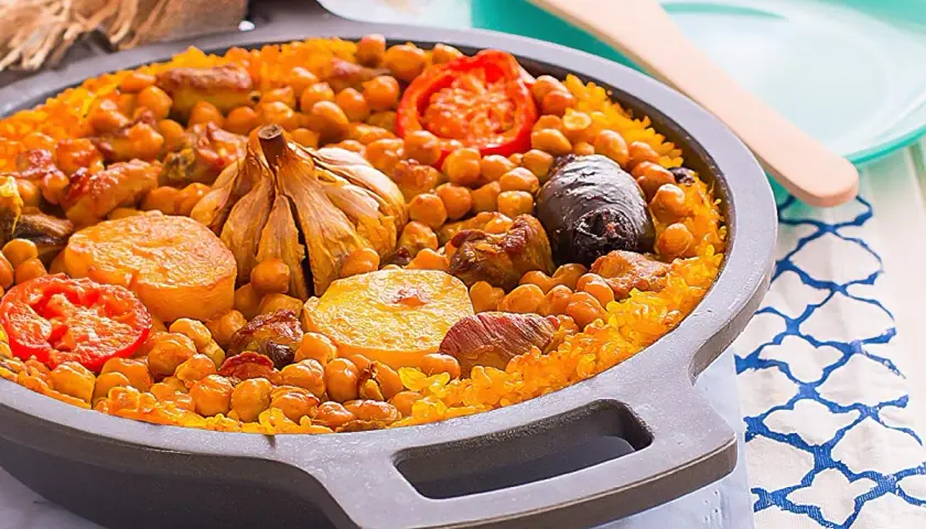 Delicioso arroz al horno con garbanzos, carne, tomate y una cabeza de ajo asada.