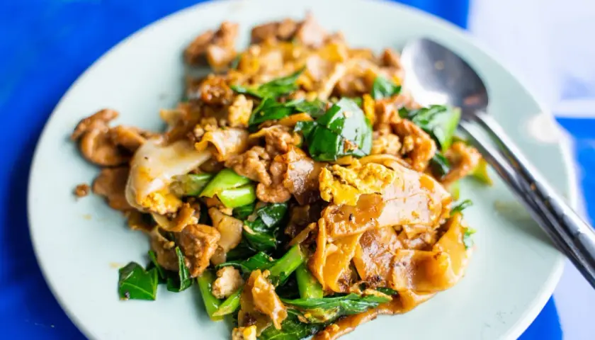 En tallrik med pad see ew, en klassisk thailändsk nudelrätt med breda risnudlar, ägg, grönsaker och kött.