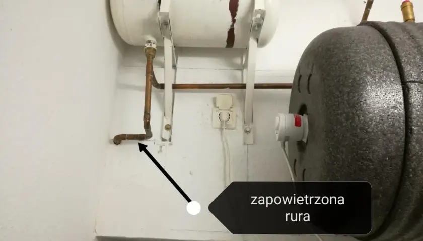 Instrukcja jak odpowietrzyć bojler przy piecu. Strzałka wskazuje zapowietrzoną rurę przy bojlerze.
