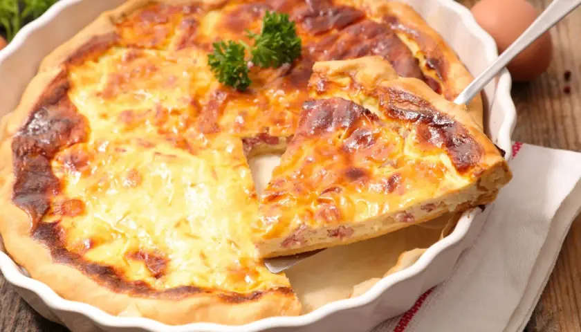 Une part de quiche lorraine dorée et appétissante, prête à être dégustée. La vraie recette quiche lorraine, un délice !